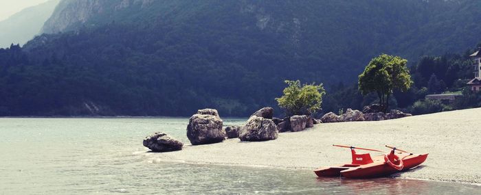 Boat moored by lake against sky