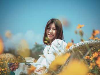 Portrait of smiling young woman against sky