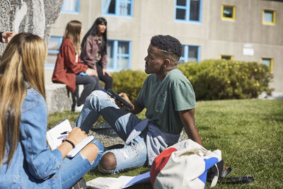 Young friends studying while university friends talking at campus