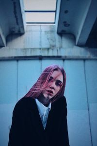 Portrait of young woman standing against wall