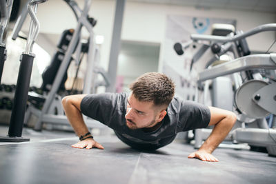 Muscular attractive guy doing push-ups in gym