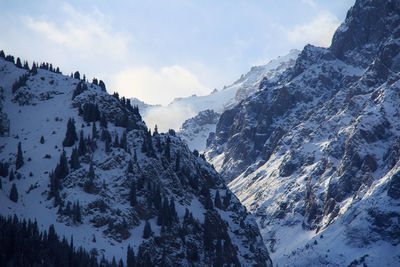 Snow-capped rocky slopes and peaks of a high-mountain gorge in winter, sunny morning