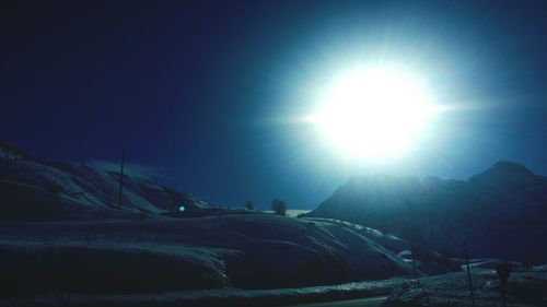 Scenic view of snow covered landscape against bright sun