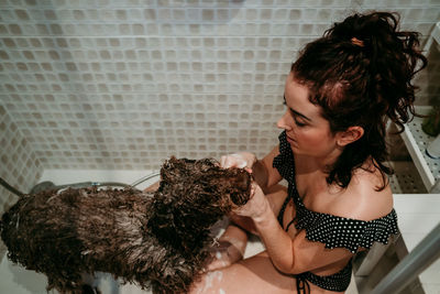 High angle view of woman bathing dog in bathroom