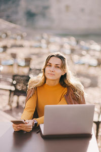 Young woman using laptop while sitting on table