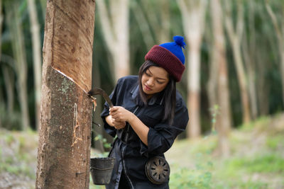 Young woman working by tree during winter