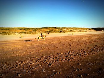 Man walking in desert against clear sky