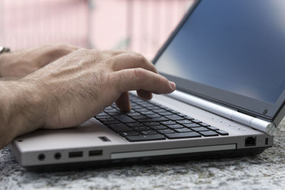 Cropped hand using laptop at table