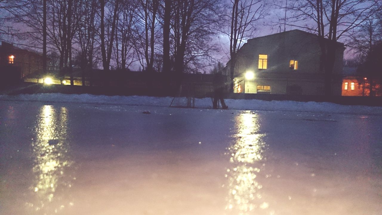 water, reflection, silhouette, tree, waterfront, bare tree, building exterior, illuminated, lake, architecture, built structure, sky, nature, night, rippled, outdoors, street light, puddle, city, river