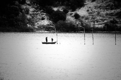 Men in boat on lake against trees