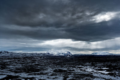 Scenic view of snow covered mountains against cloudy sky