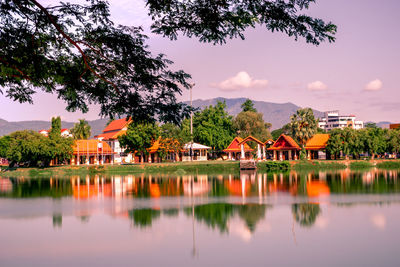 Houses by lake and buildings against sky