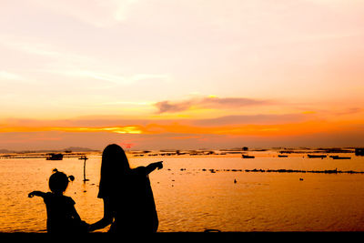 Silhouette people on beach against sky during sunset