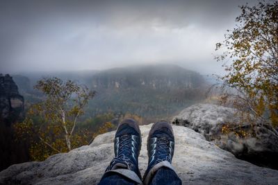 Low section of person on mountain against sky