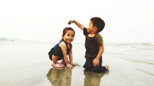 Boy enjoying on beach against sky