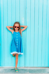 Portrait of smiling girl standing against blue wall