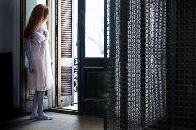 Young woman standing by door at home