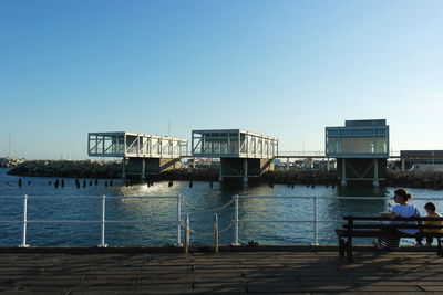 Men by sea against clear sky