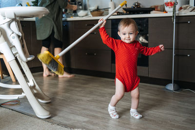 Little mothers helper. cute toddler baby girl with mop help her mom do housework in kitchen. cute