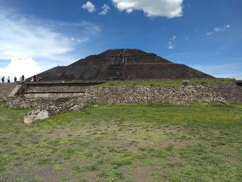 Built structure on landscape against cloudy sky