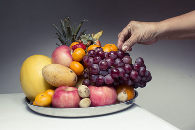 Close-up of hand holding grapes over white background