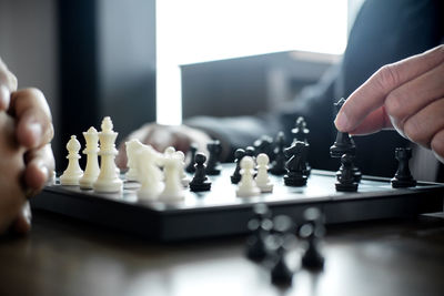 Midsection of man playing chess with friend at home