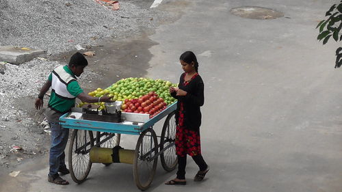 High angle view of woman buying fruits from street vendor
