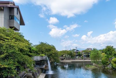 Houses by river and buildings against sky