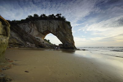 Rock formation on beach against sky