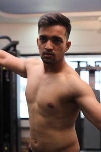 Shirtless young man flexing muscles in gym