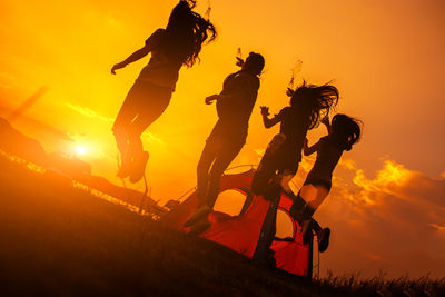 Silhouette people riding motorcycle against sky during sunset