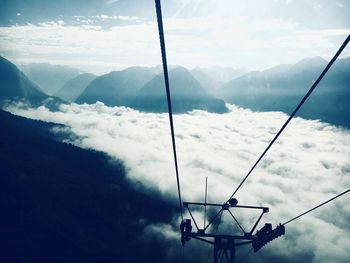 Low angle view of overhead cable car against mountains