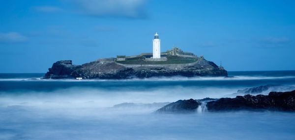 Lighthouse by sea against sky