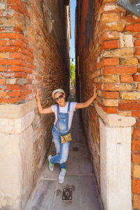 Full length portrait of boy standing against brick wall