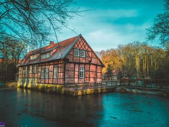 Houses by lake and buildings against sky