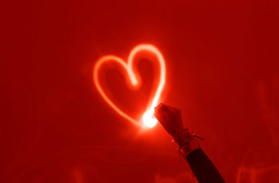 Close-up of hand holding heart shape red fire