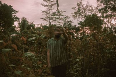 Woman standing on field against trees