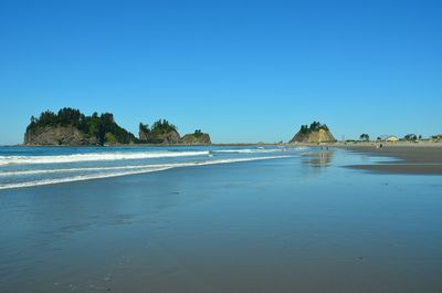 Scenic view of beach against clear blue sky