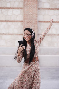Young woman with mobile phone standing outdoors