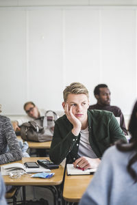 Young man sitting with hand on chin in classroom