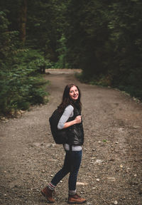 Full length portrait of young woman standing on road