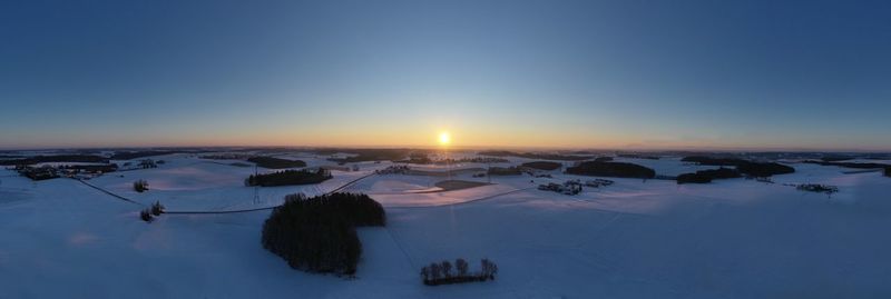 High angle view of snow covered landscape against sky during sunset