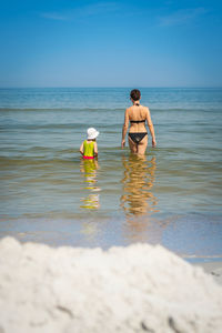 Full length of shirtless man standing in sea against sky