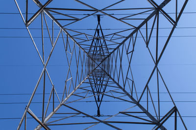 Low angle view of electricity pylon against clear blue sky