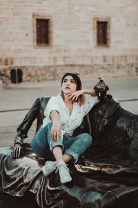 Full length of woman sitting against building