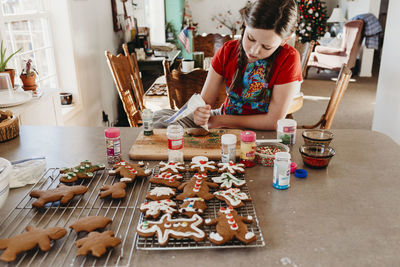 Girl decorating christmas cookies with icing and sprinkles