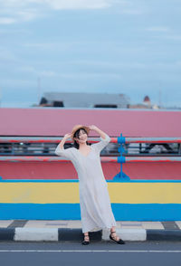 Rear view of woman with arms raised standing against sky