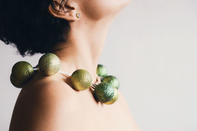 Midsection of topless mature woman wearing green necklace against white background