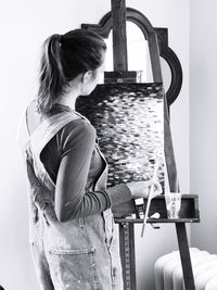 Rear view of woman standing against wall at home