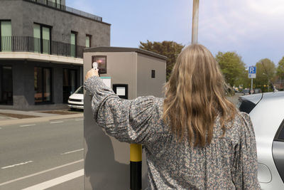 Rear view of woman standing on road in city